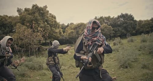 Squad of armed terrorists patrolling a forest area during combat