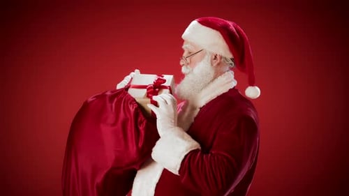 Santa Claus Holds Gift from Bag on Red Background