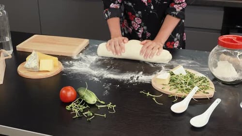 Frau rollt Teig mit den Händen. Frau in der Profiküche bereitet Teig mit Mehl für Pizza
zu