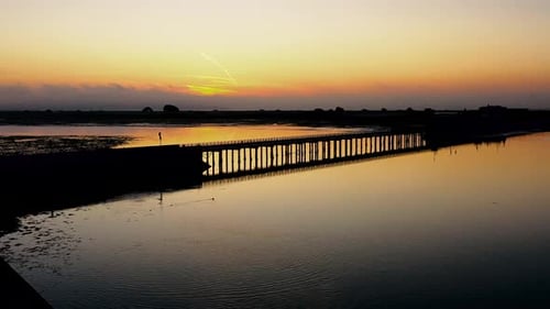 Sunrise over Pier Reflecting in Calm Water