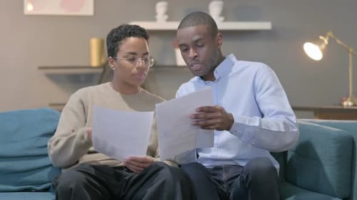 Man and Woman Discussing Papers on Couch