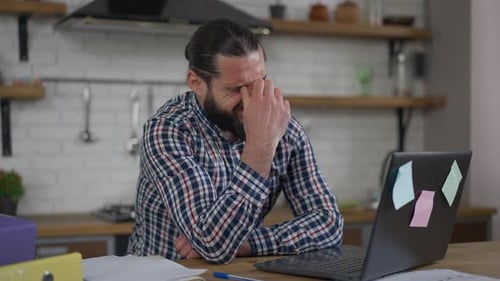 Portrait of Overburdened Bearded Handsome Middle Eastern Man Rubbing Eyes Stretching Neck Typing on