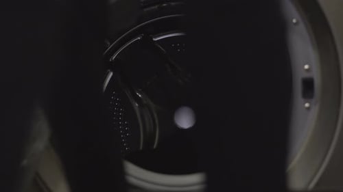 Person Loading Clothes Into Front Load Washing Machine