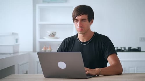 Young Adult Man Typing on a Laptop Indoors