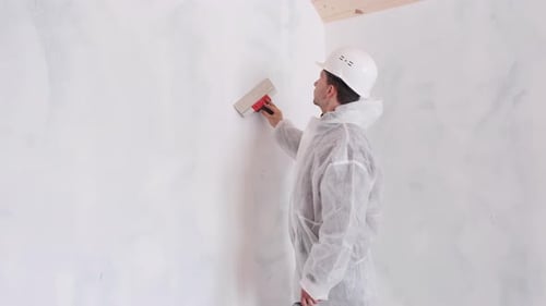 Man Applying White Plaster to Wall