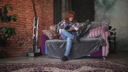 Auburn-Haired Young Adult Plays Bass Guitar at Home