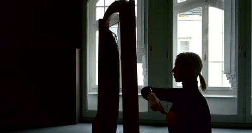 Ein junges schlankes blondes Mädchen ist in einem großen Studio mit großen Fenstern, sie sitzt am Gong und schlägt