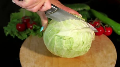 Nahaufnahme einer Frau schneidet ein Messer in halben Kohl auf einem Schneidebrett