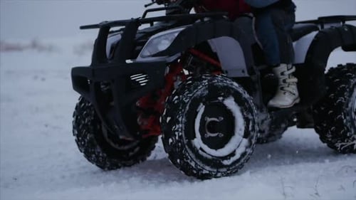 ATV Four-Wheeler Driving Through Snowy Winter Field