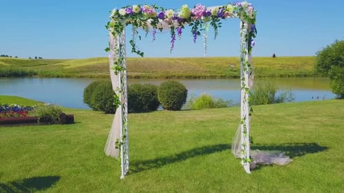 Wedding Arch with Fresh Flowers on Green Lawn Close View