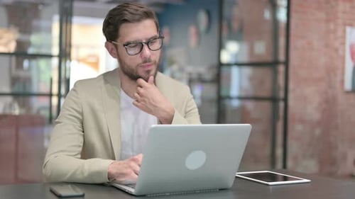 Man Thinking at Desk Using Laptop Computer