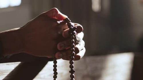 Close Up of Hands Holding Rosary Beads