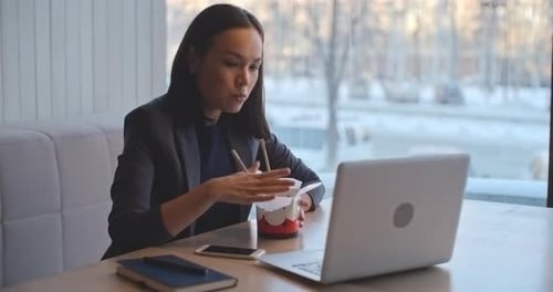 Woman Eating Lunch and Working on Laptop