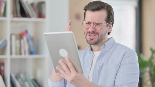 Man Confused While Using Tablet Indoors