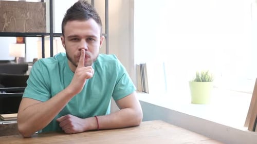 Gesture of Silence by Young Man, Finger on Lips