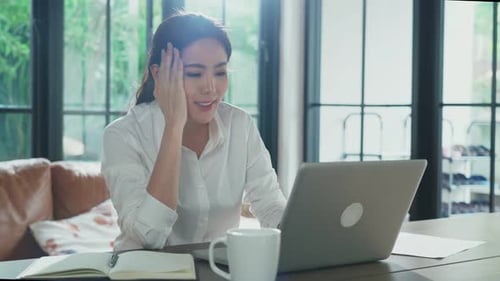Portrait of Asian businesswoman feeling boring unhappy while working on computer at home.