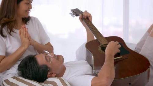 Relaxed Man Plays Guitar for Woman at Home