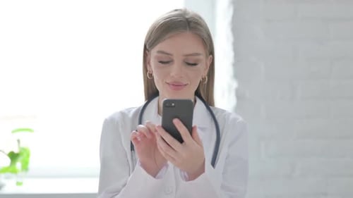 Female Doctor Using Smartphone in Hospital Setting