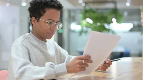 Young Woman Reviews Documents at Office Desk