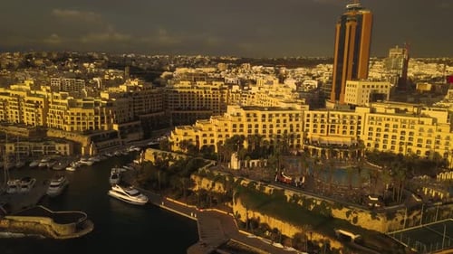 Beautiful golden light of sunrise shines on the buildings of San Giljan along the coast of Malta. Re
