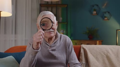 Senior Man Looking Through Magnifying Glass Indoors