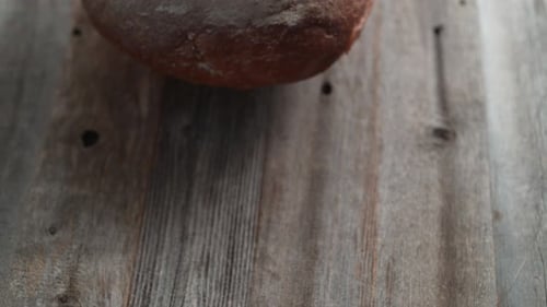 Ein ganzes Sauerteigbrot fällt auf einen Tisch. Zeitlupe.