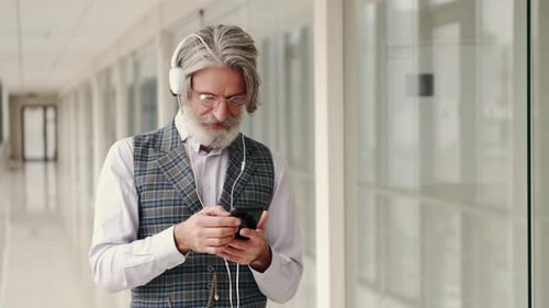 Senior Man Using Smartphone in Office Corridor