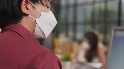 Young people with face masks back at work in office after lockdown