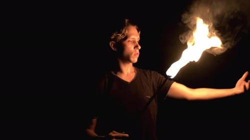 Man Juggling a Flaming Torch in Darkness