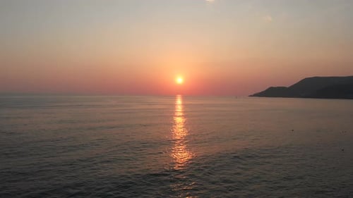 beautiful sunset on the background of sea, sun going beyond the horizon illuminating water