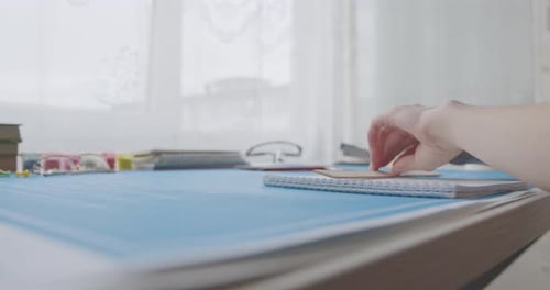A young woman works and studies architecture from blueprints. She draws with a pencil in a notebook