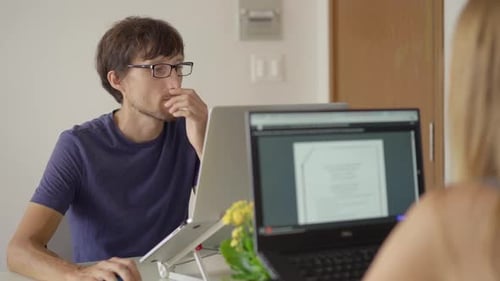 Man Working on Laptop With Coworker at Desk
