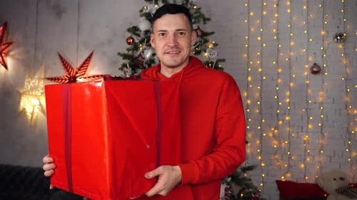 Man Holding a Christmas Gift in Decorated Home
