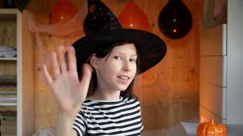 Girl in Witch Hat Waving at Halloween Party