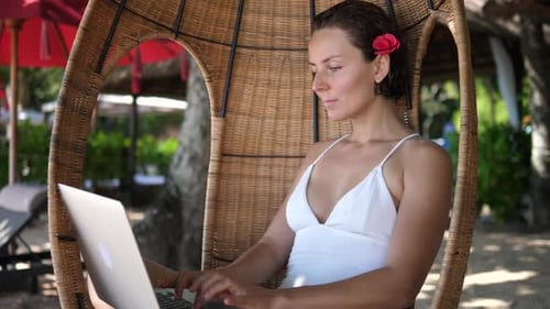 Digital Nomad Concept Weiße Frau arbeitet von einem Strand aus an ihrem Laptop
