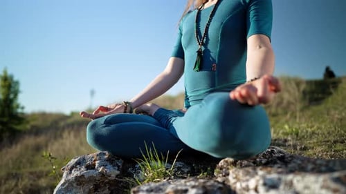 Woman Meditating in Lotus Pose on Rock