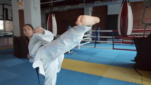 Woman Practicing Karate Kicks and Blocks in Gym