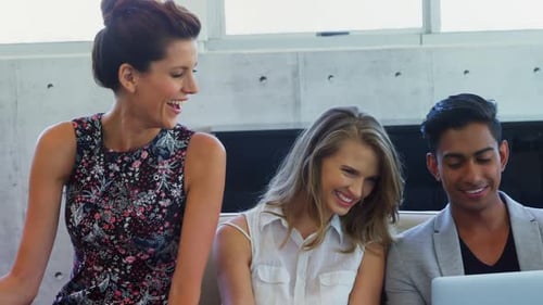 Business team looks at a laptop, smiles