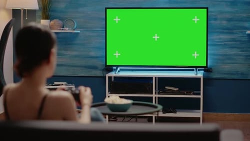 mujer joven, utilizar, controlador, en, pantalla verde, tv