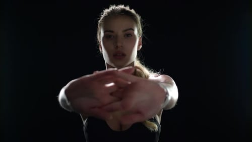 Fitness Woman Doing Stretch Exercise for Hands in Black Studio. Sport Woman