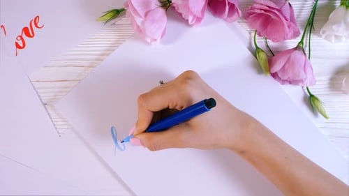Calligrapher hands writes word beauty on white paper. Inscribing ornamental decorated letters.