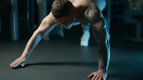 A Handsome Young Muscular Sportsman is Doing Exercise on a Fitness Machine in the Gym