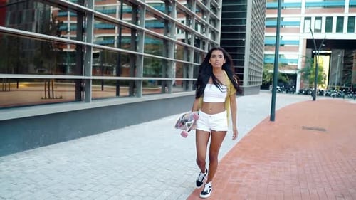 Pretty Athletic Girl Rides a Longboard in Modern City