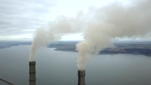Aerial view of high chimney pipes with grey smoke from coal power plant. Production of electricity