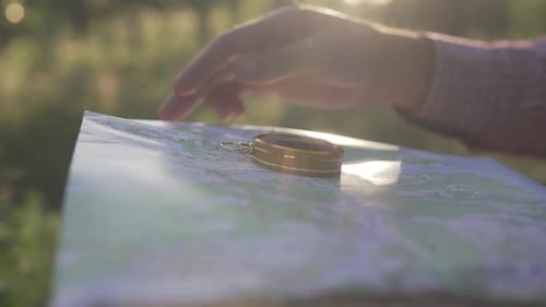Hand Points at Map in the Countryside at Sunset