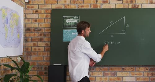 Portrait of caucasian male teacher teaching mathematics in the classroom at school