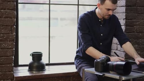 Man Using Stylus and Tablet Near a Window