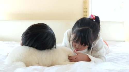 Children with Puppy Lying on Bed Together