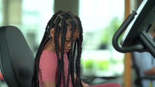 Young Girl Using Recumbent Bike in a Bright Gym