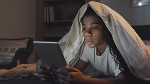Fille utilisant la tablette au lit